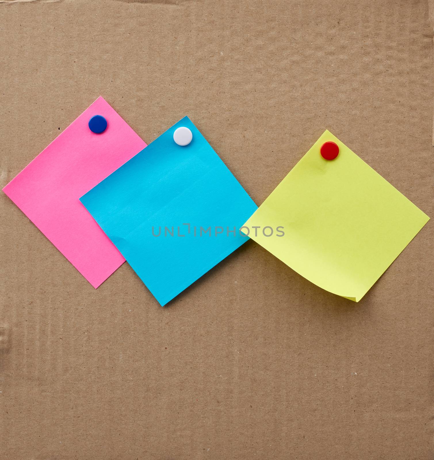 blank square sheets of paper stickers attached with an iron button on a brown cardboard surface. Design template.