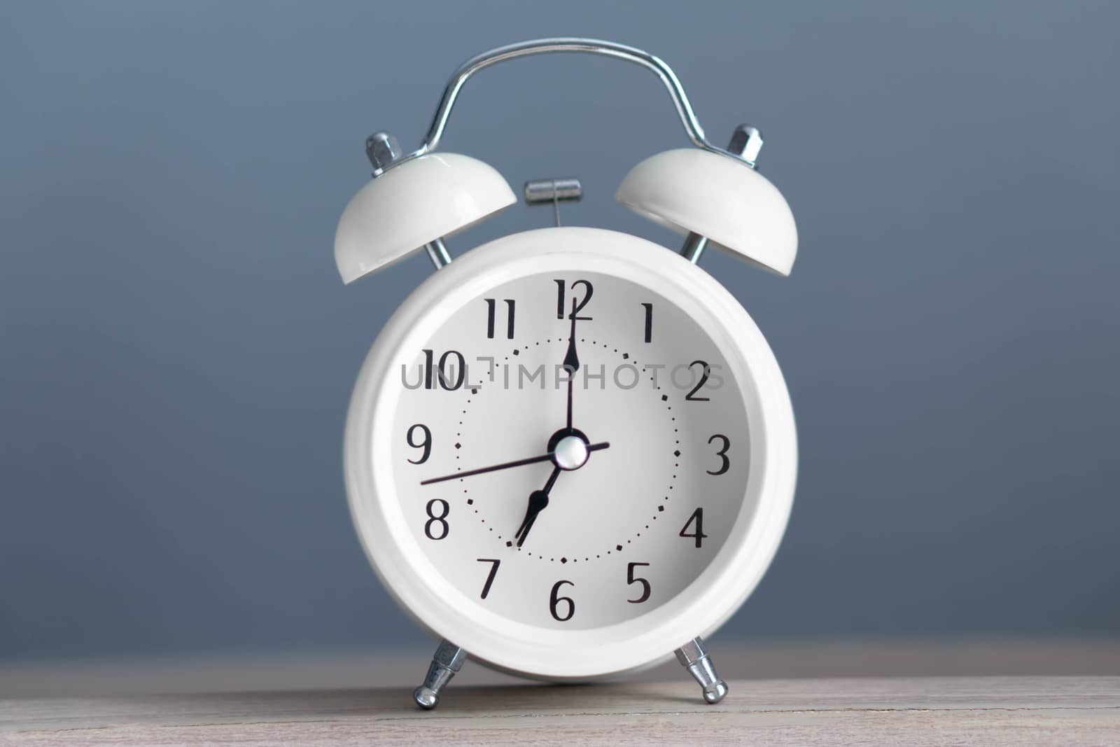 Alarm clock on wooden table with grey background, selective