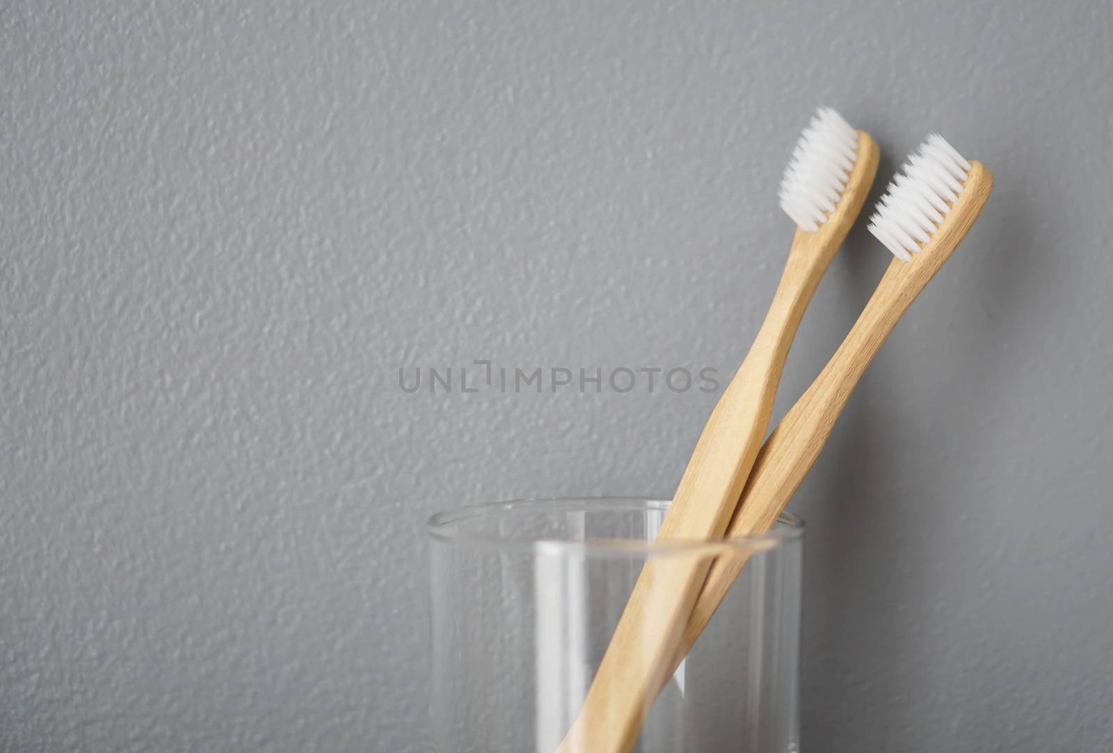 Close up wooden toothbrush in glass with grey background, select by pt.pongsak@gmail.com
