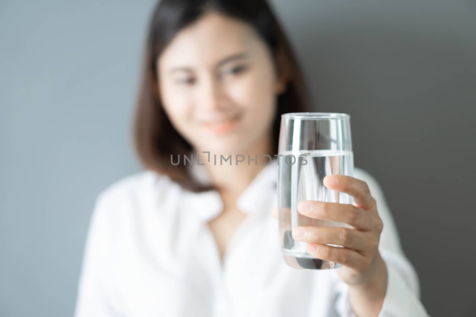 Close up woman hand holding glass of pure water with smile face background, Selective focus