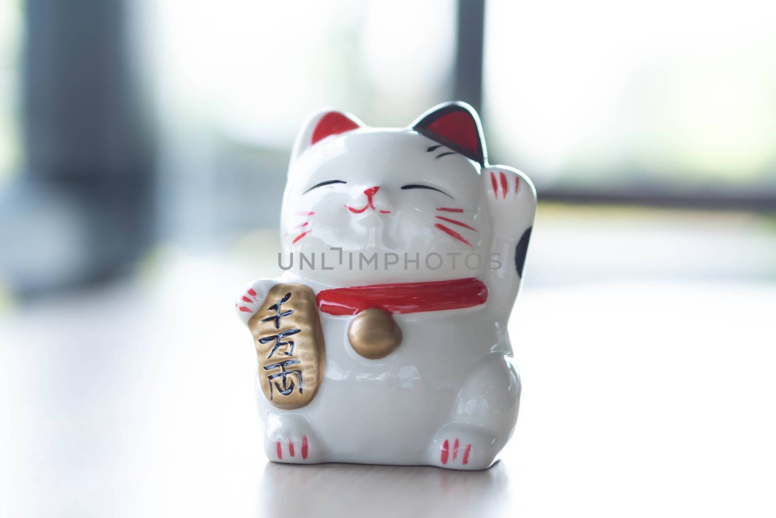 Maneki neko lucky cat show text on hand meaning rich on wood table background, select focus