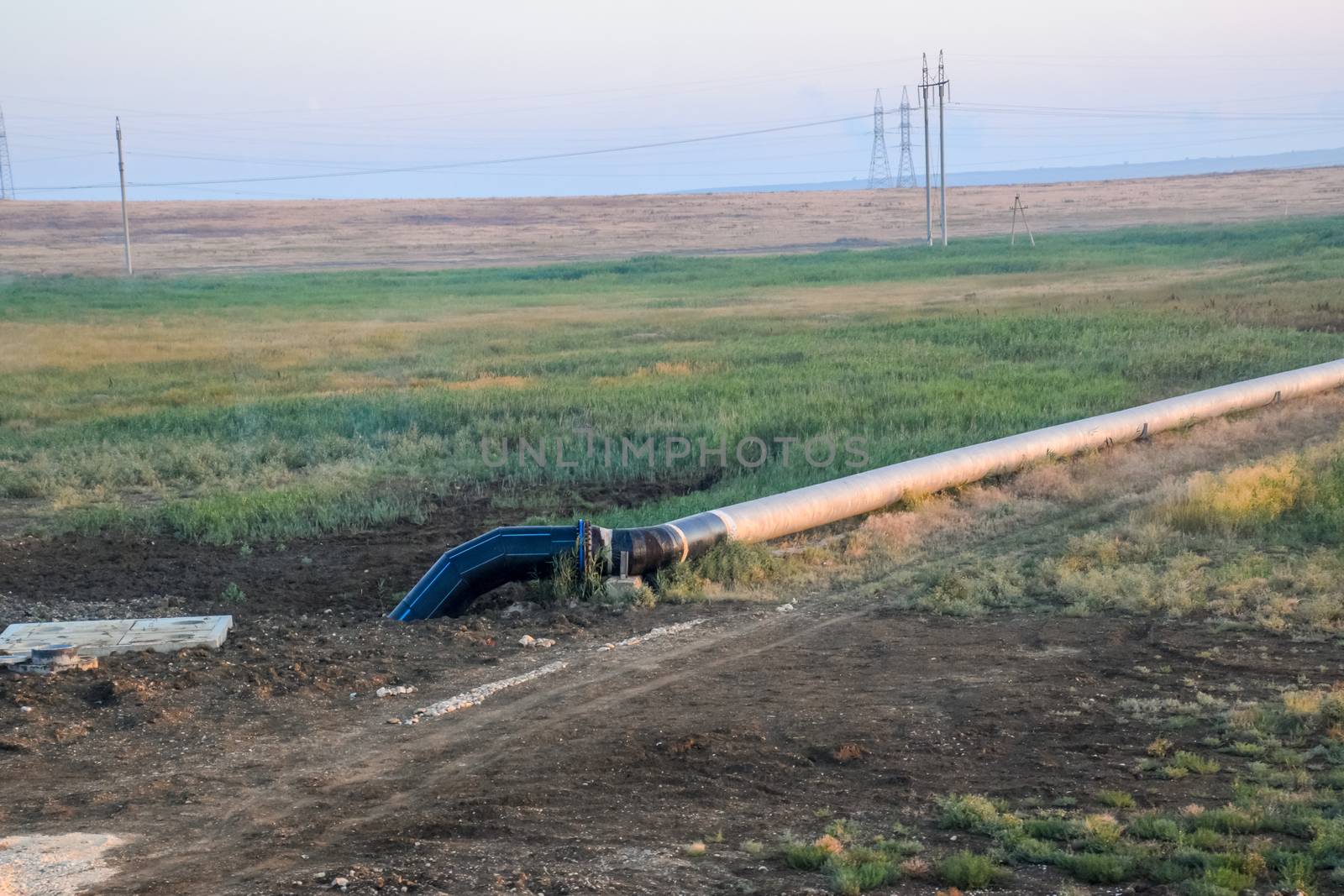 A gas pipeline in the field. The pipe goes on the surface and goes underground.