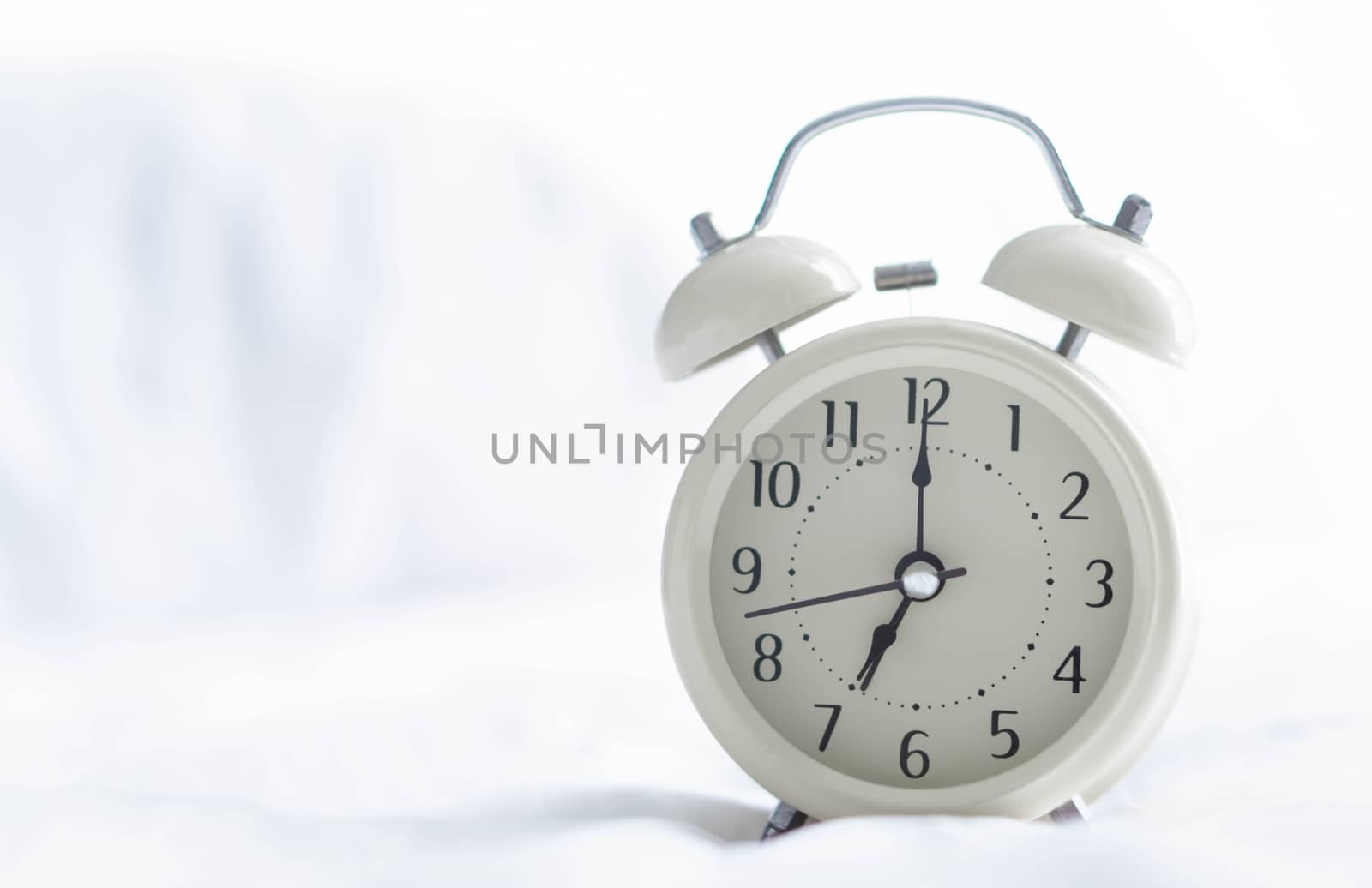 Alarm clock on wooden table for wake up time with light from window, selective focus