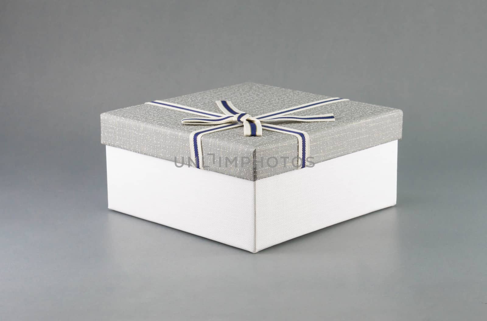 Grey gift box with ribbon on grey background, copy space