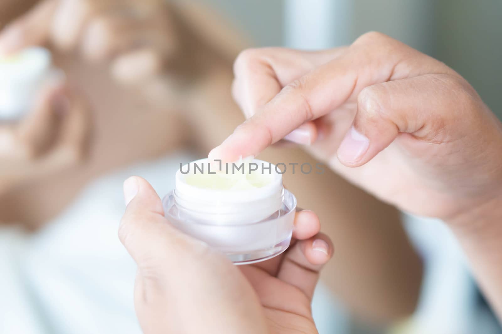 Close up woman hand applying cream or moisturizer from box for face beauty, selective focus