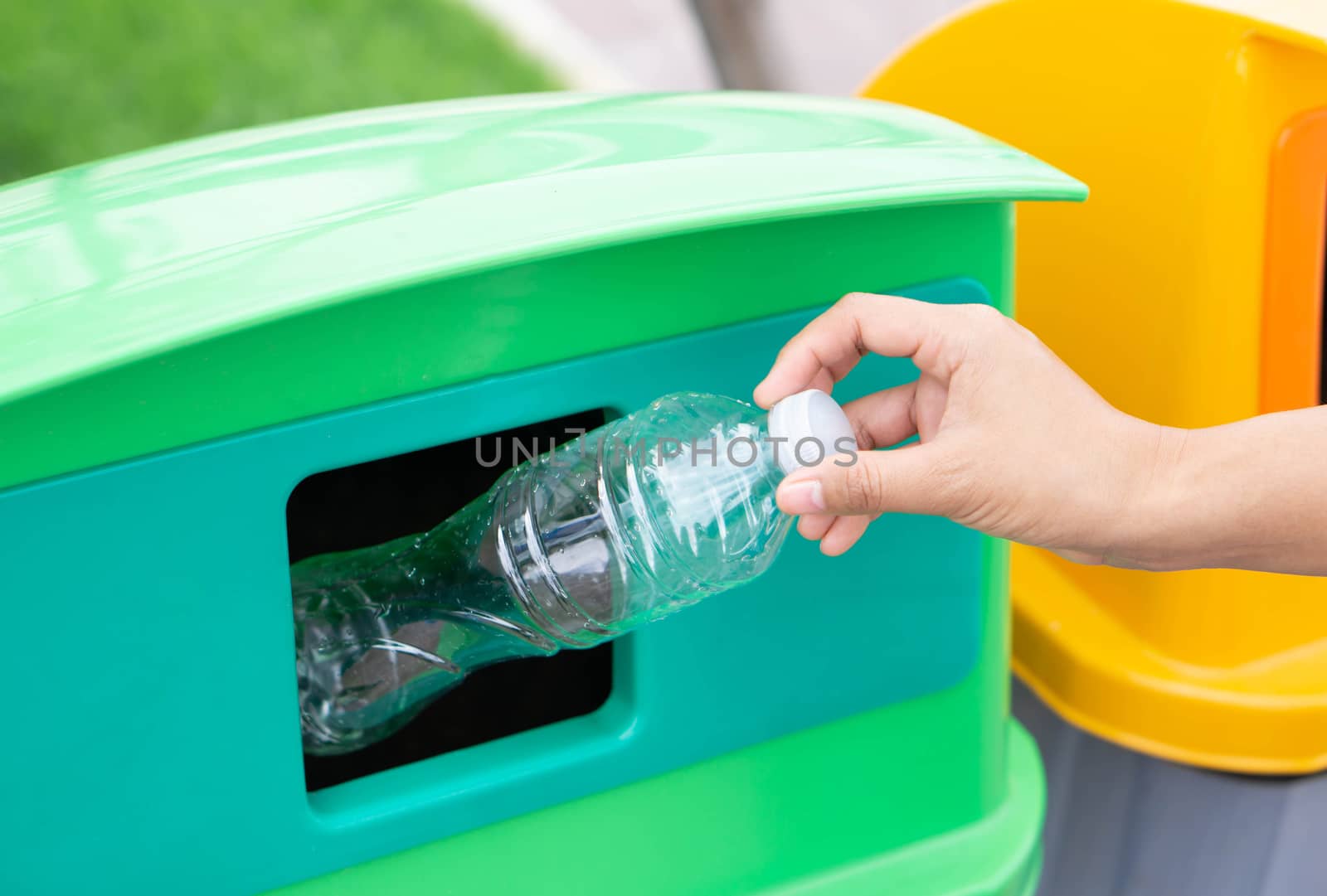 Close up hand holding garbage plastic bottle into recycle trash bin, selective focus