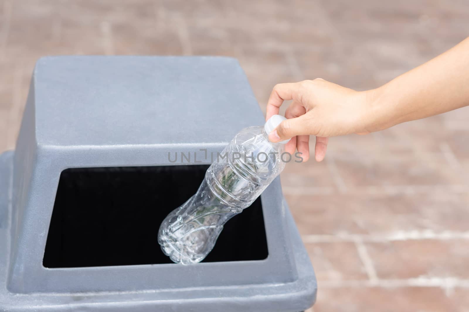 Close up hand holding garbage plastic bottle into recycle trash bin, selective focus