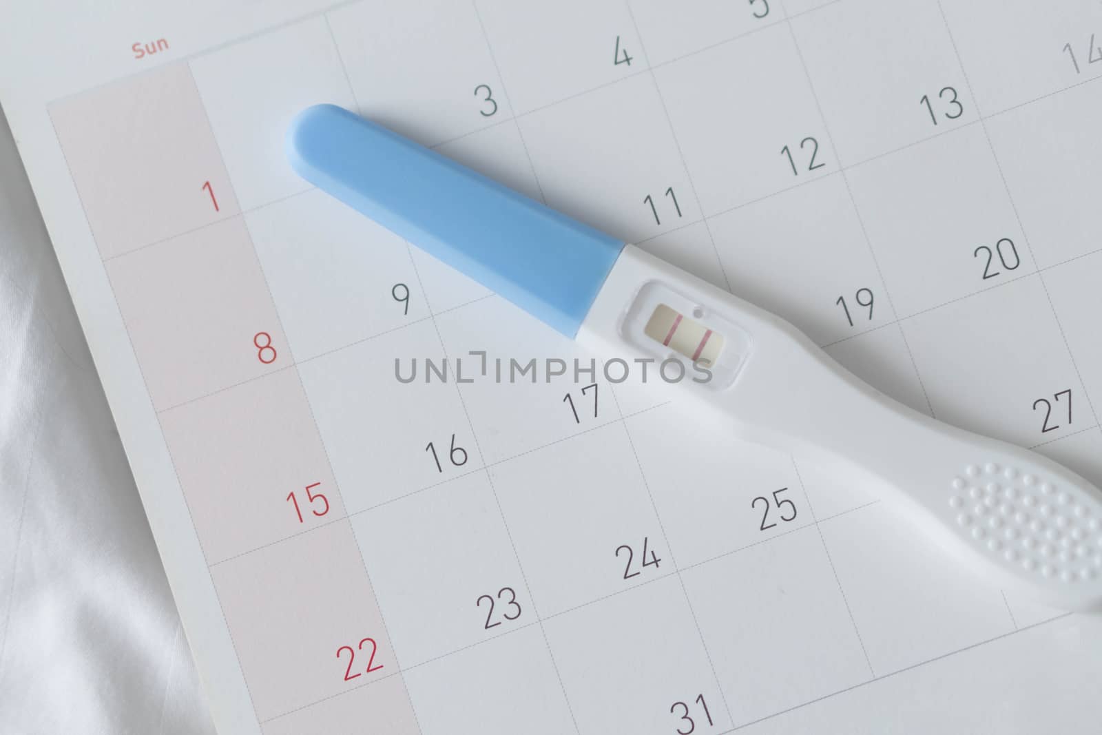 Pregnancy test on calendar background, health care concept