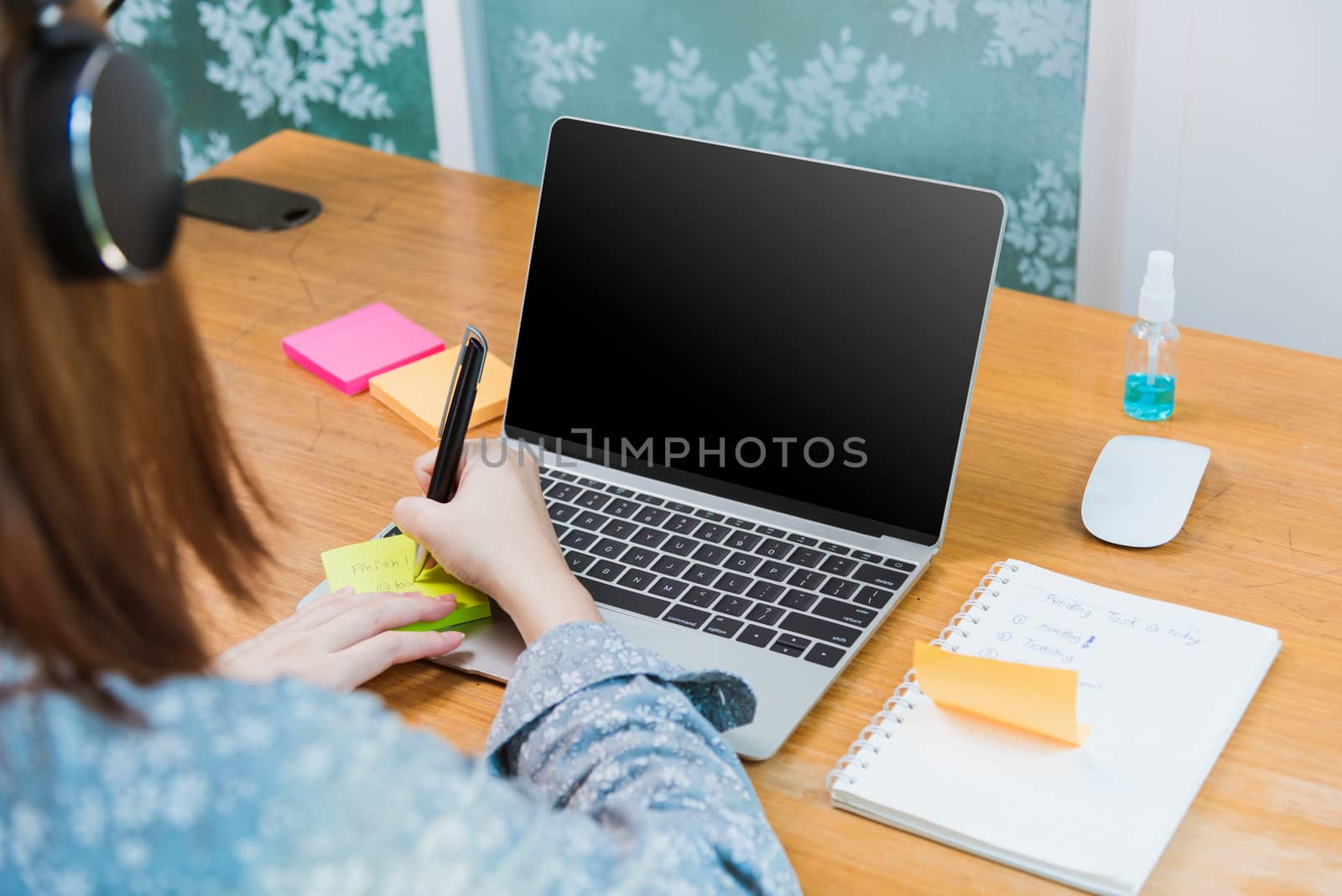 Asian young business woman wearing face mask protective working from home office with laptop computer he quarantines disease coronavirus or COVID-19 and write note stick memory work today