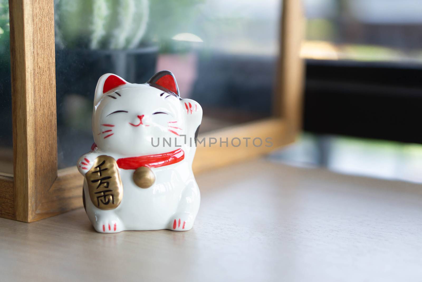 Maneki neko lucky cat show text on hand meaning rich on wood table background, select focus