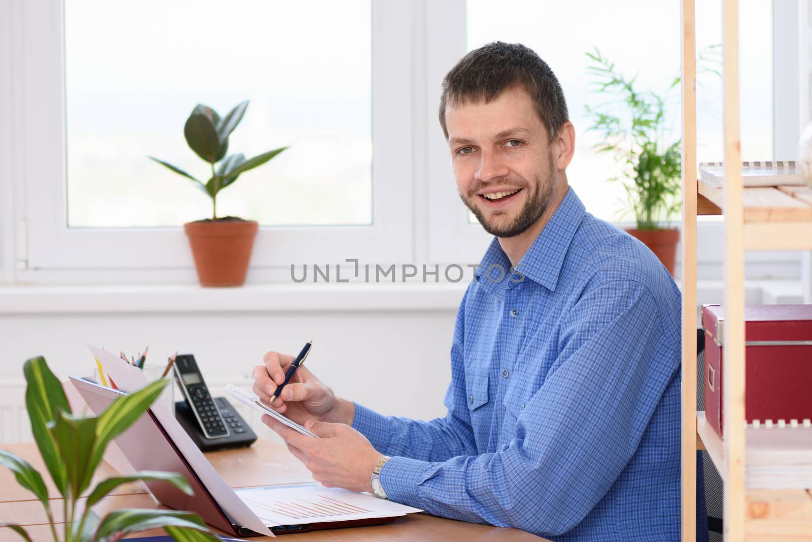 Young successful businessman writes in a notebook and looked into the frame
