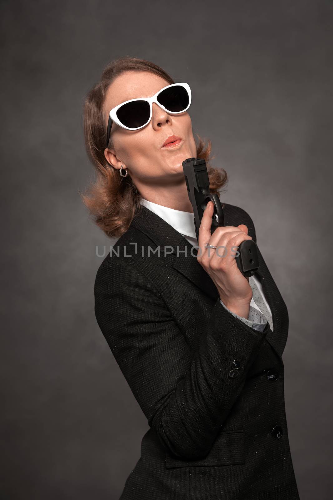 criminal policewoman in civilian clothes with a gun in her hand. portrait with dark background.