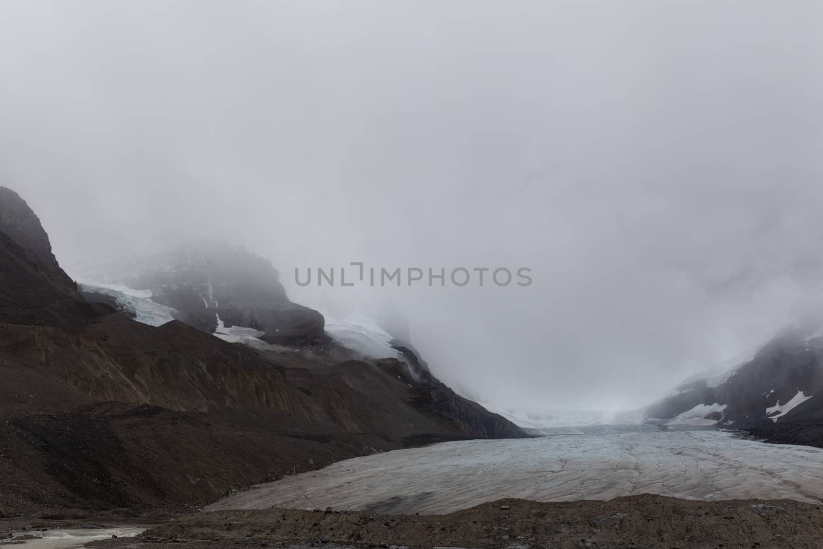 Athabasca glacier covered with fog sliding from the mountains, Alberta, Canada