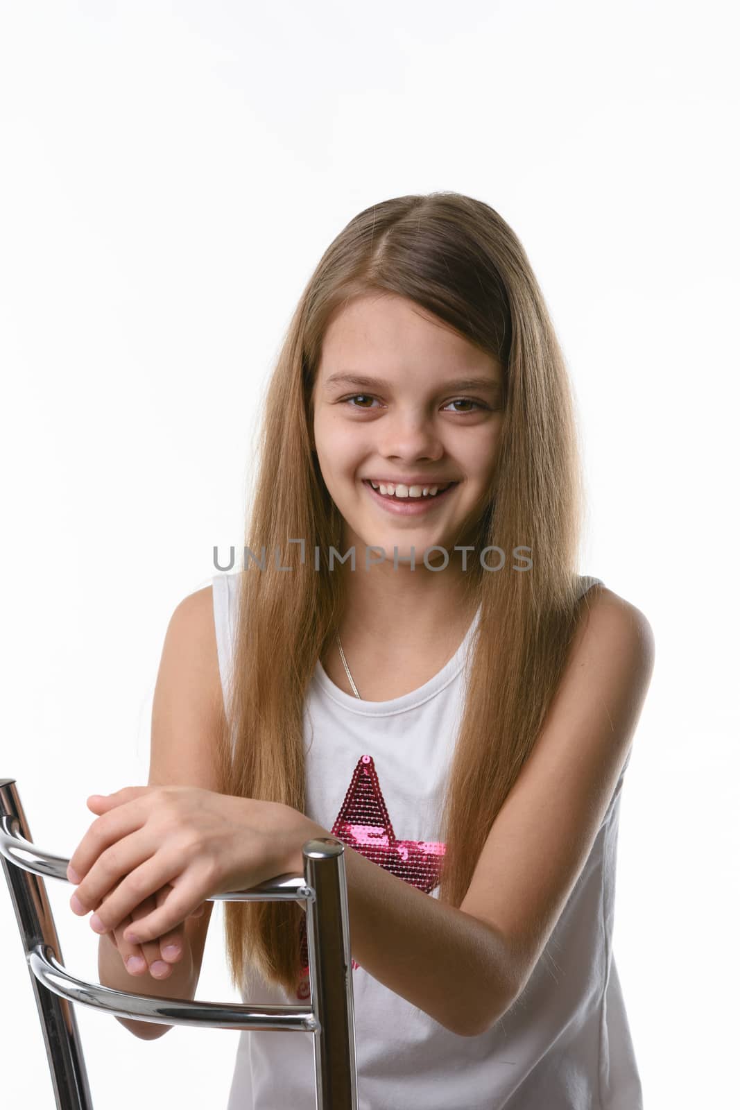 Girl sitting on a high-backed chair and smiling joyfully