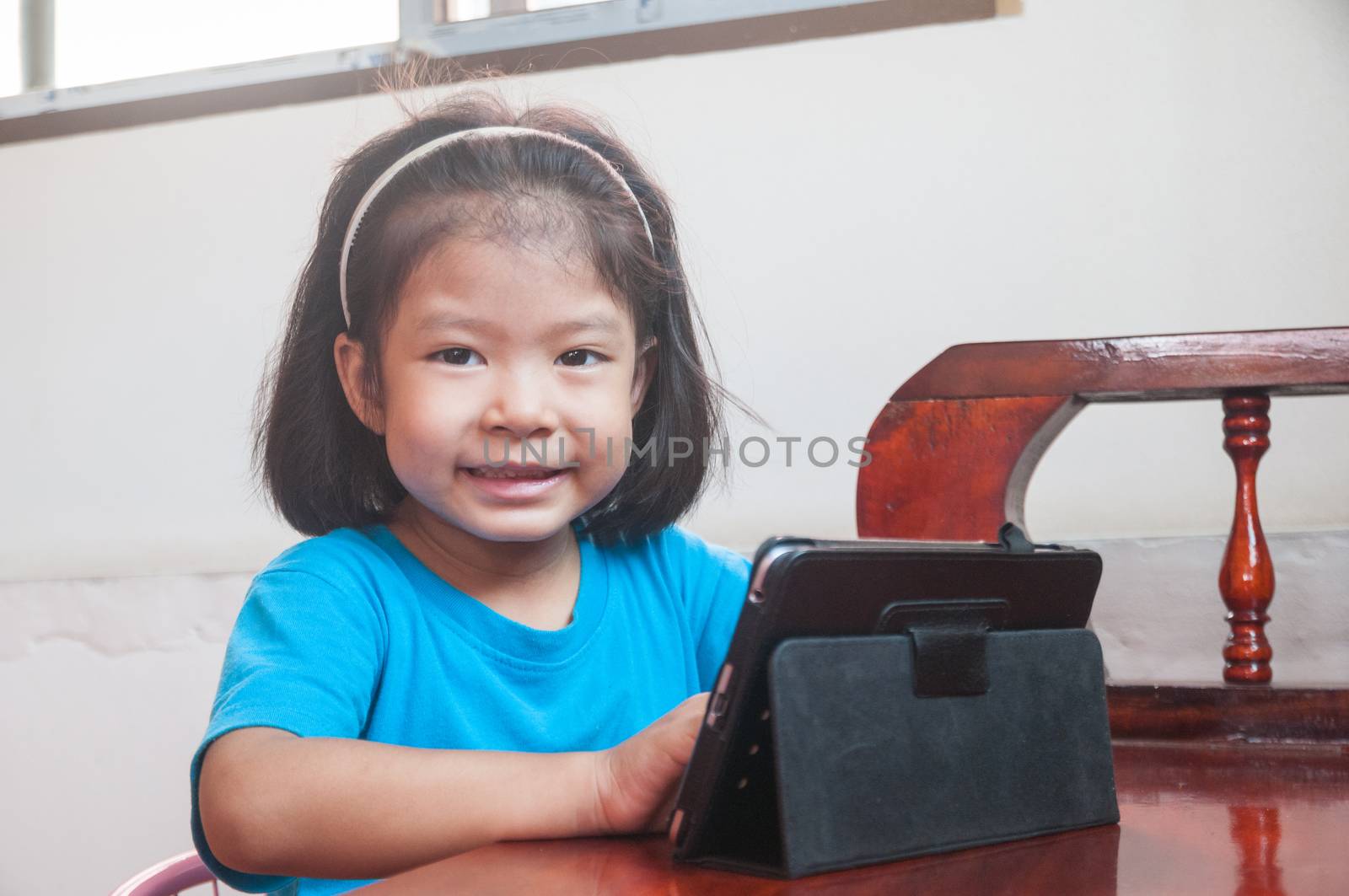Asian Girl learning online course or playing game online on Digital Wireless Device or Tablet at home as Technology e-learning concept.