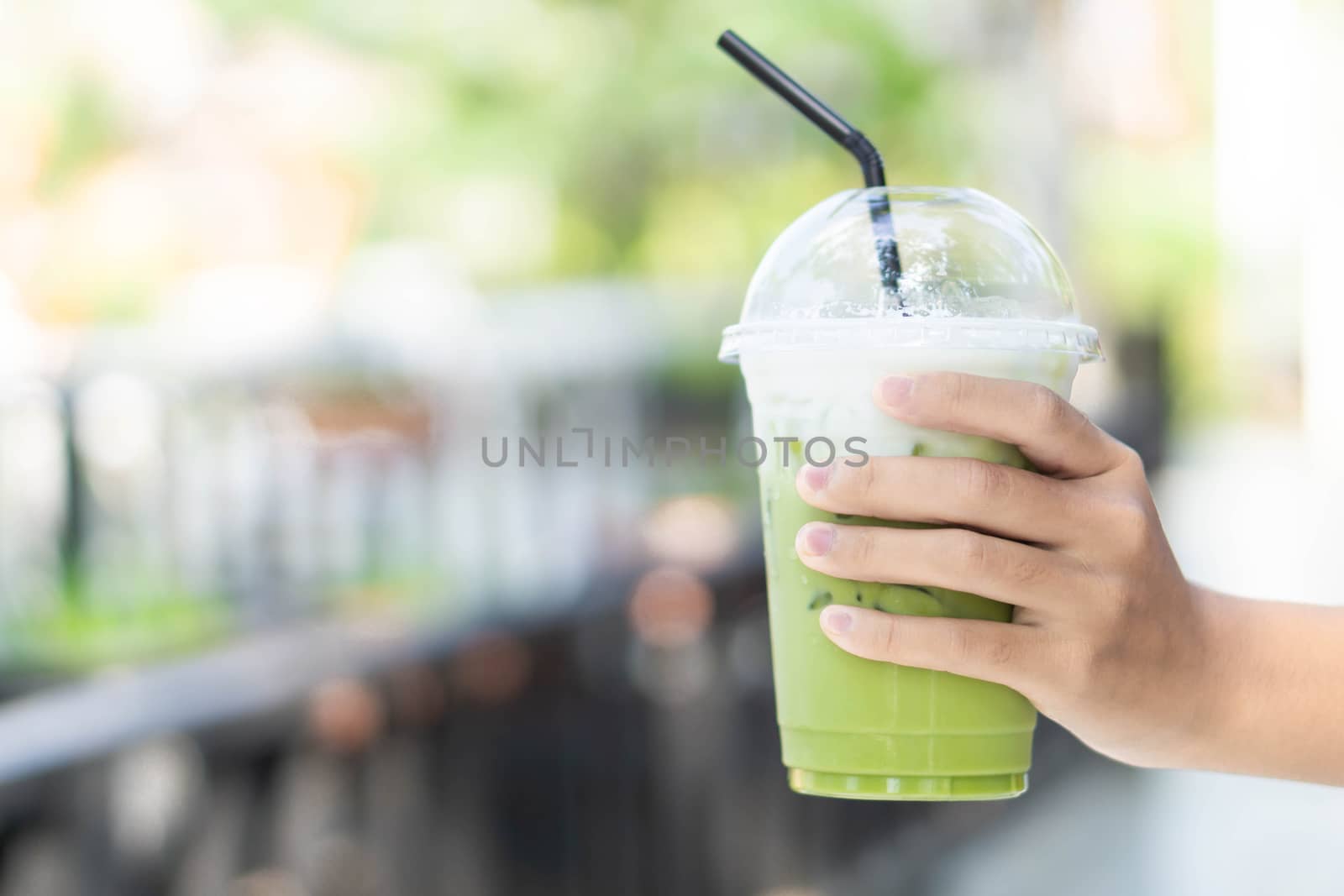 Close up glass of ice matcha green tea on hand, selective focus