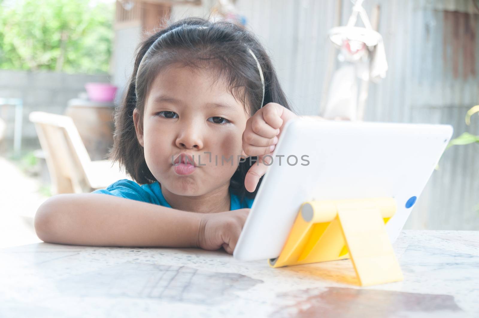 Asian Girl feeling unhappy while learning online course or playing game online on Digital Wireless Device or Tablet at home as Technology e-learning concept.