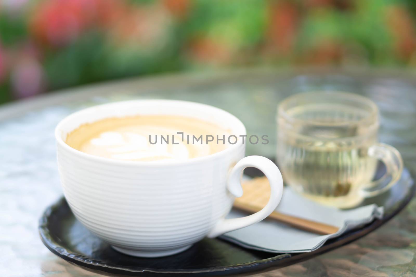 Closeup glass of latte art coffee tulip shape on glass table with flower background