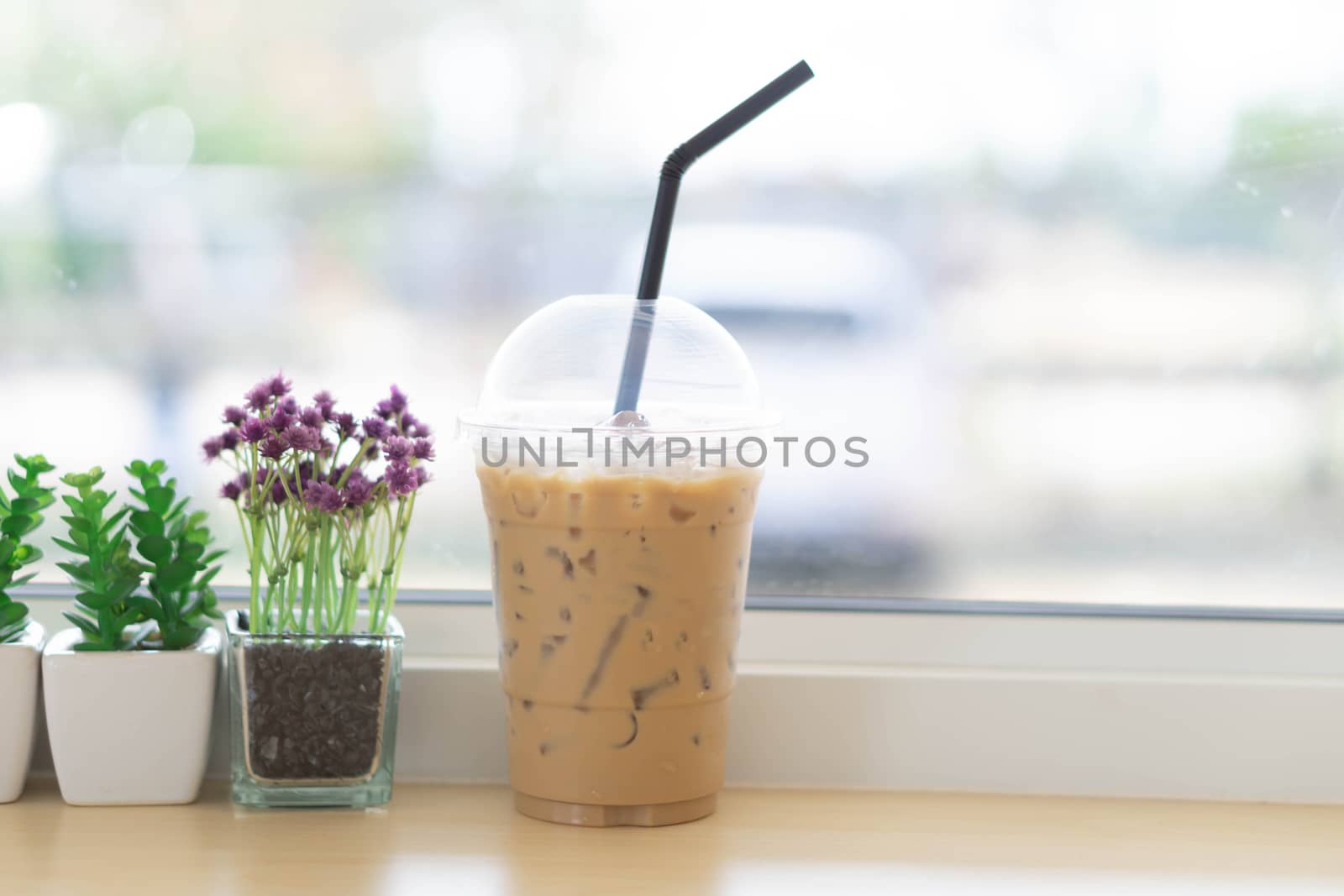 Closeup glass of ice coffee with flower pot in the coffee shop