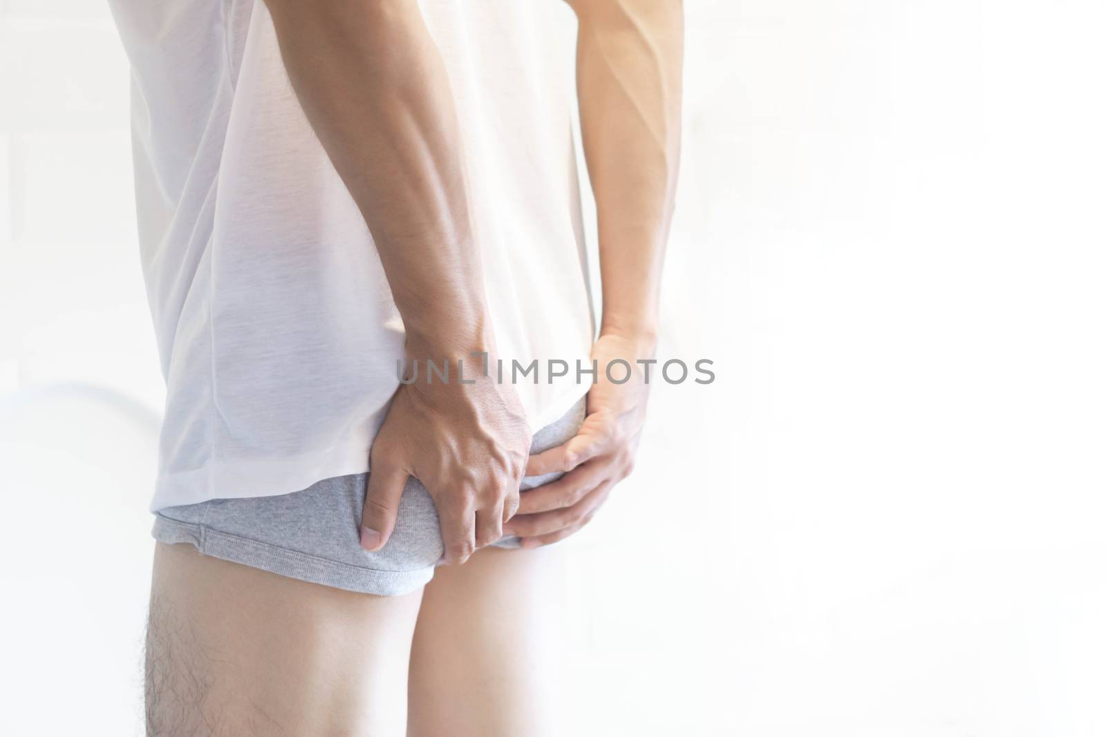 Closeup man holding bladder with pee pain in the toilet, selective focus