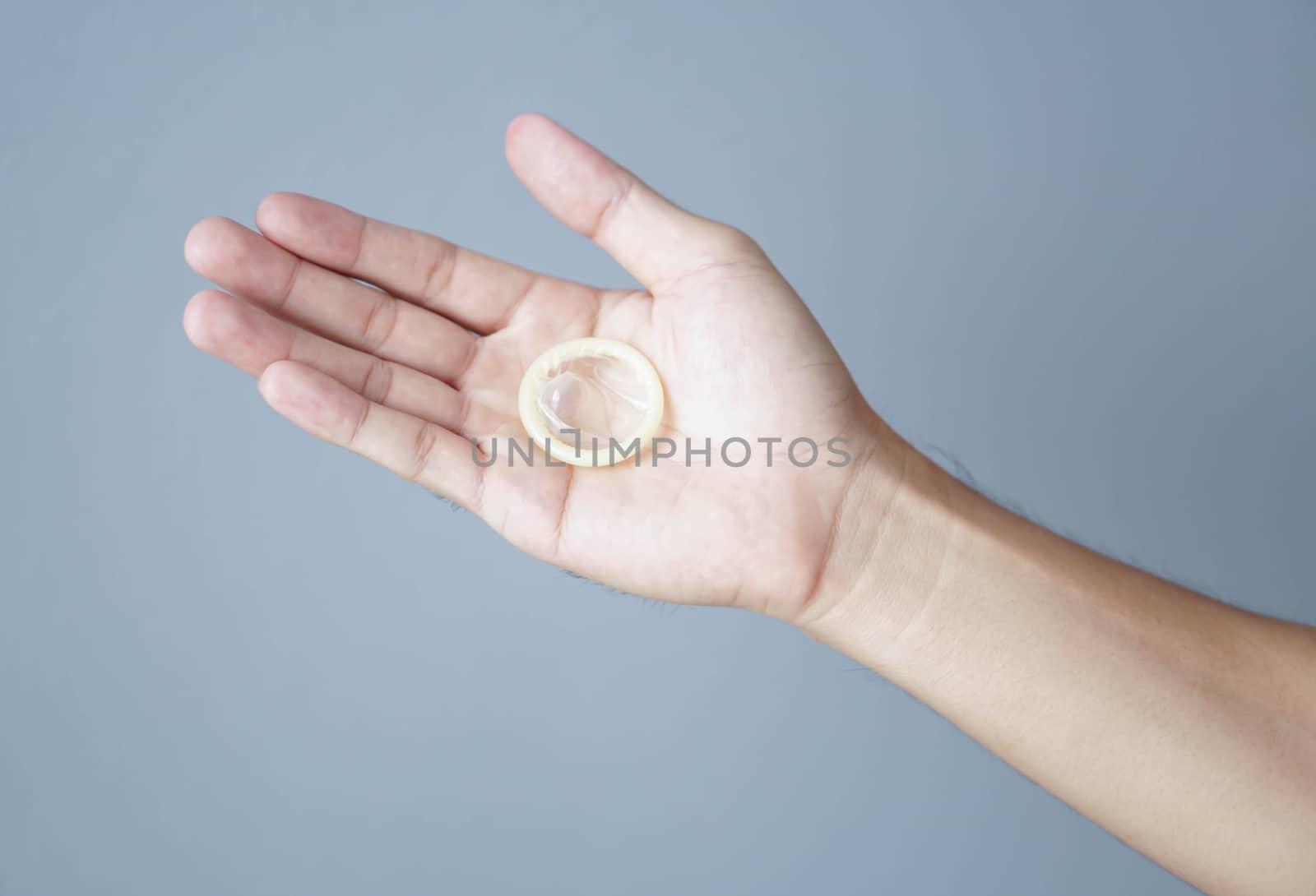 Close up woman hand holding condom lying on white bed, health care and medical concept
