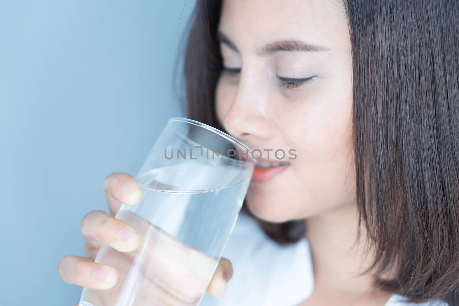 Close up woman drinking pure water from glass with light in the  by pt.pongsak@gmail.com