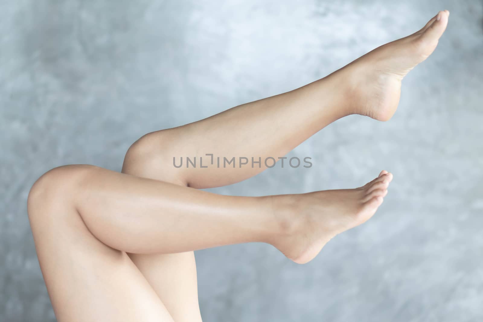 Closeup woman legs relaxing with grey background, beauty and skin care concept, selective focus