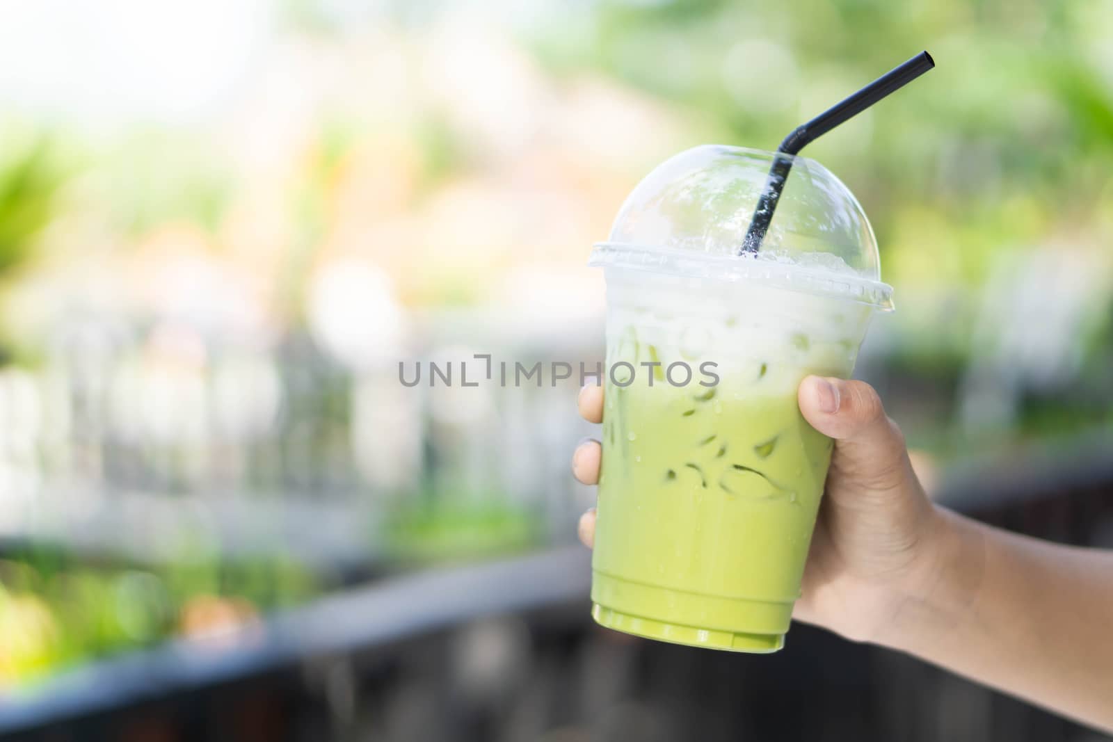 Close up glass of ice matcha green tea on hand, selective focus