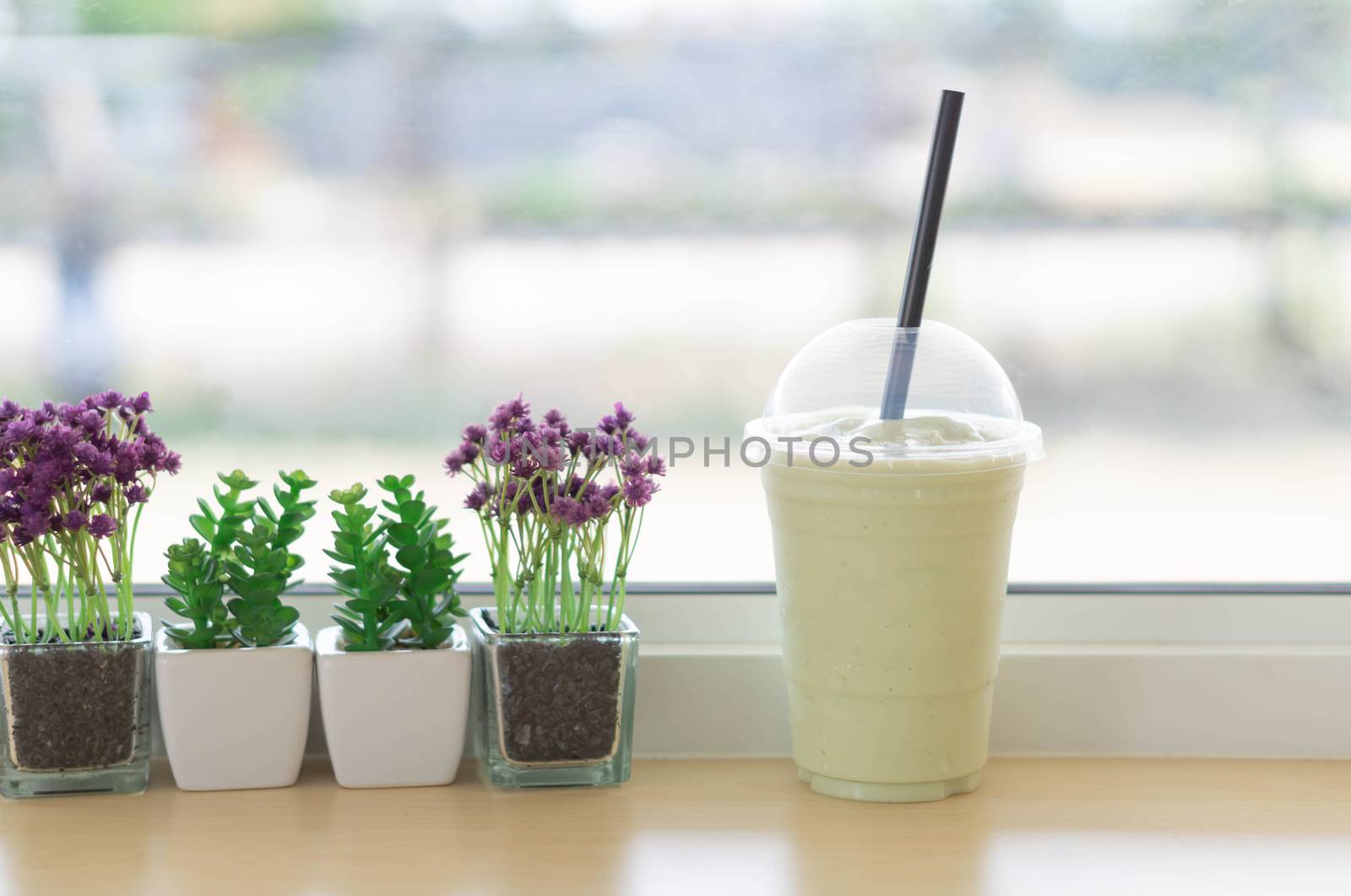 Clsoeup glass of avocado frappe or smoothie with flower pot in the coffee shop, selective focus