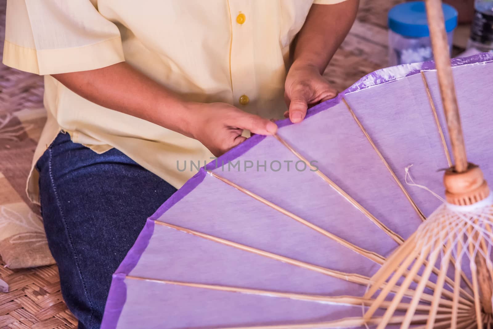 Worker cover and glue with persimmon ferment on Handmade umbrella of the village Bo Sang, Chiang mai, Thailand.