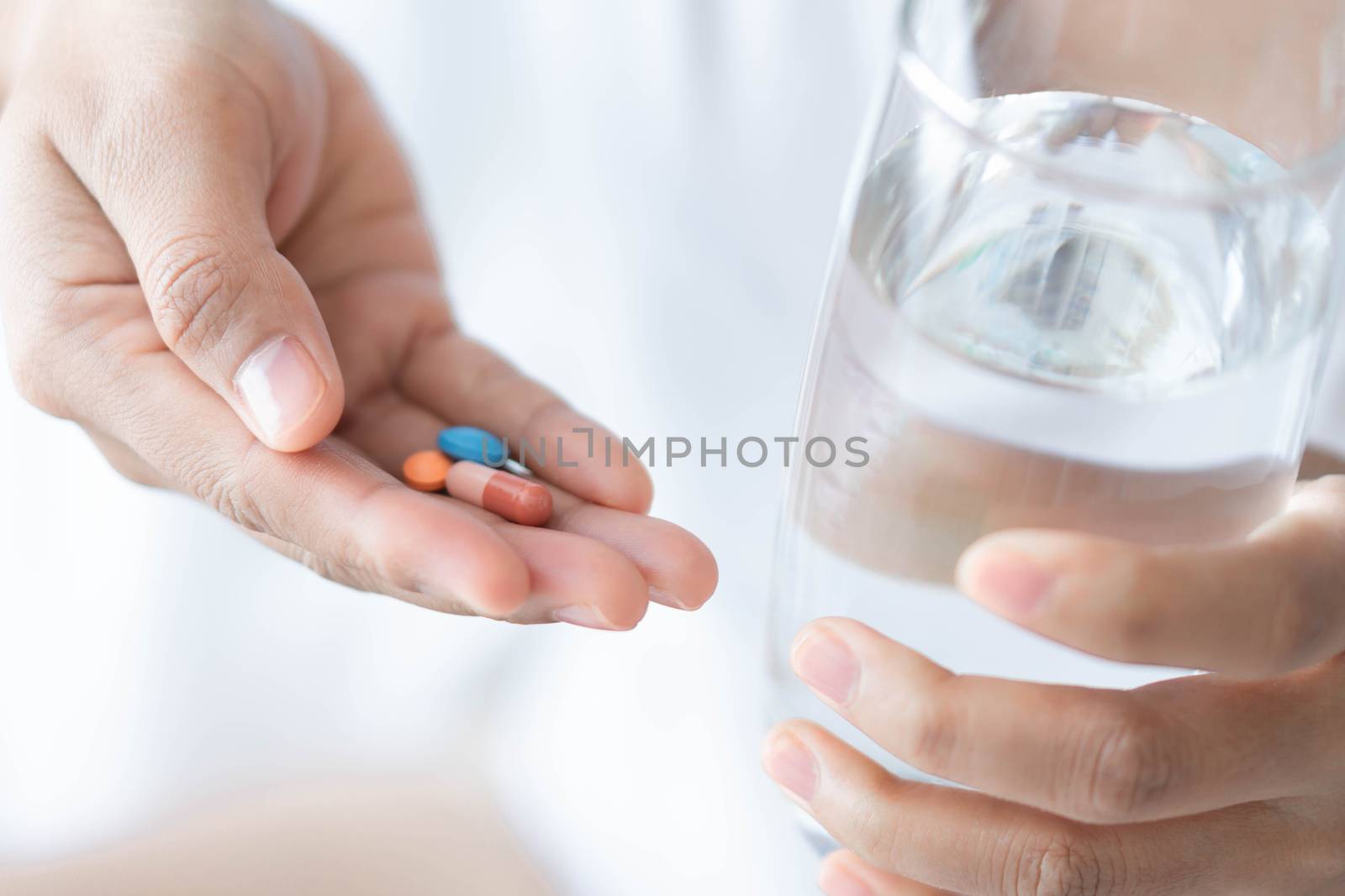 Closeup woman hand holding pills and glass of water, health care and medical concept, selective focus