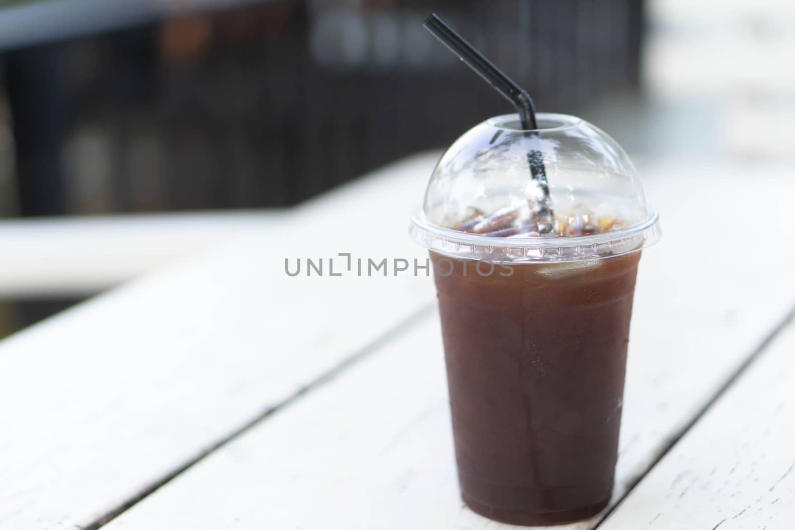 Close up glass of ice americano coffee on wood table, selective focus