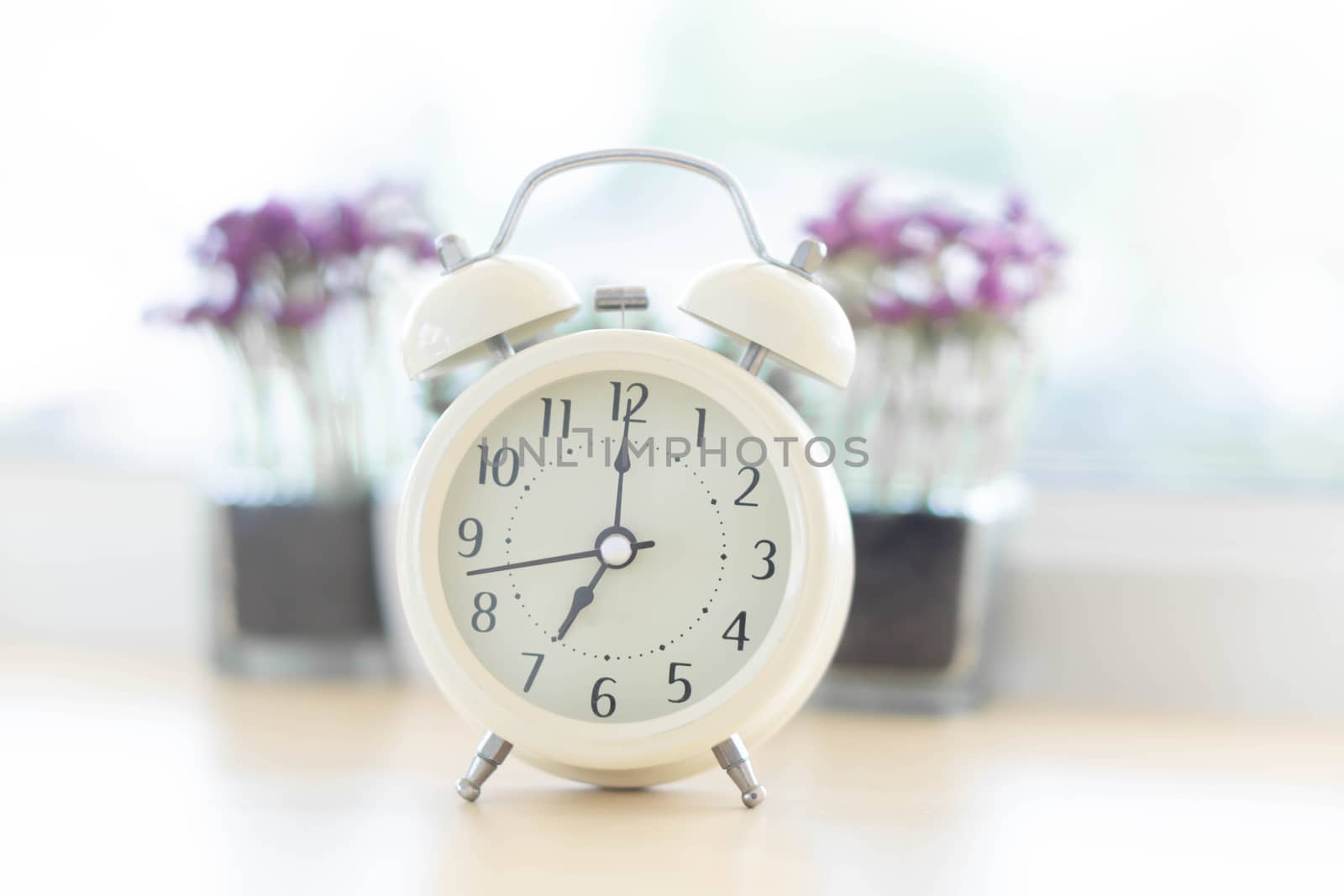 Alarm clock on white table with soft light in the morning, selective