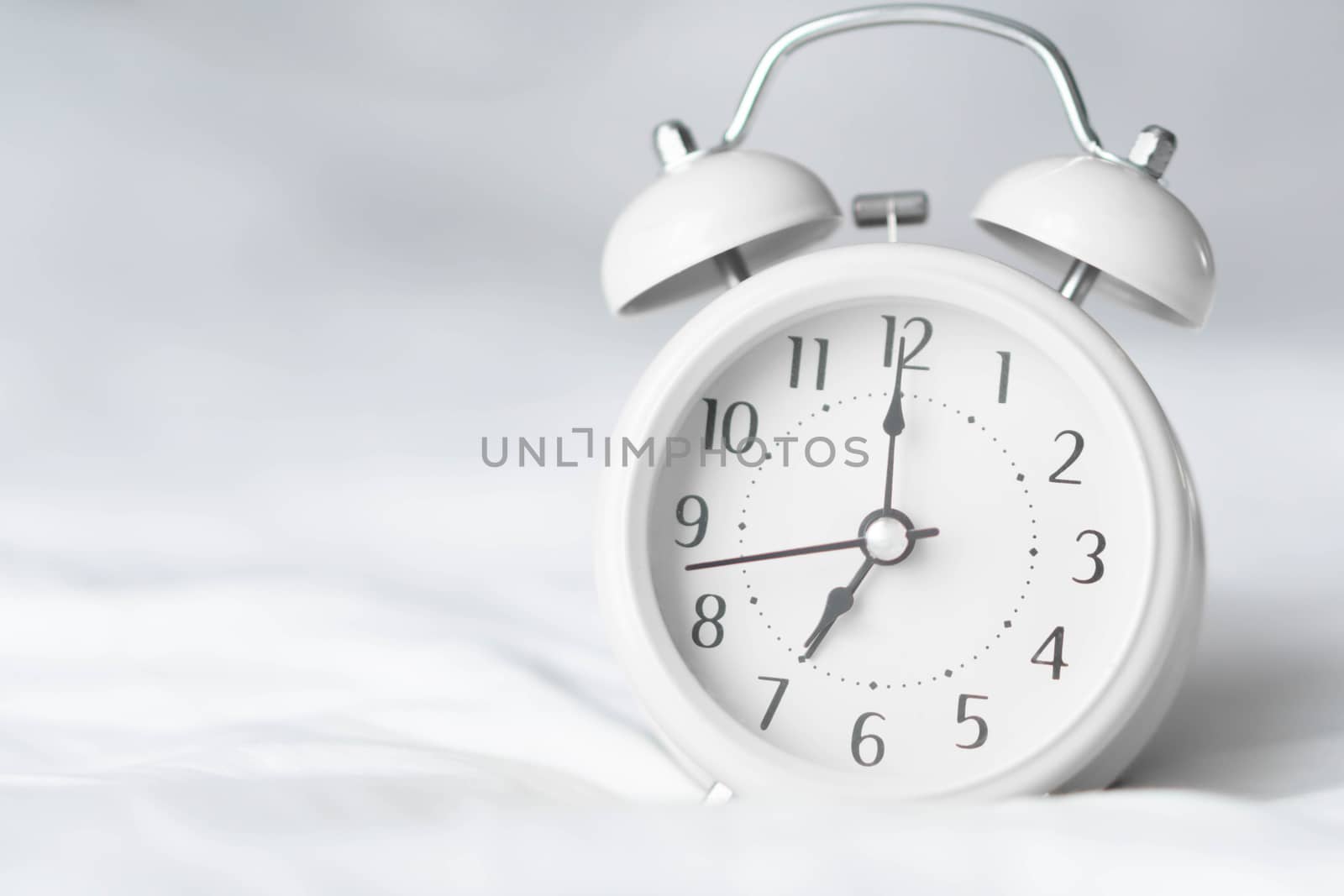 Alarm clock on wooden table for wake up time with light from window, selective focus