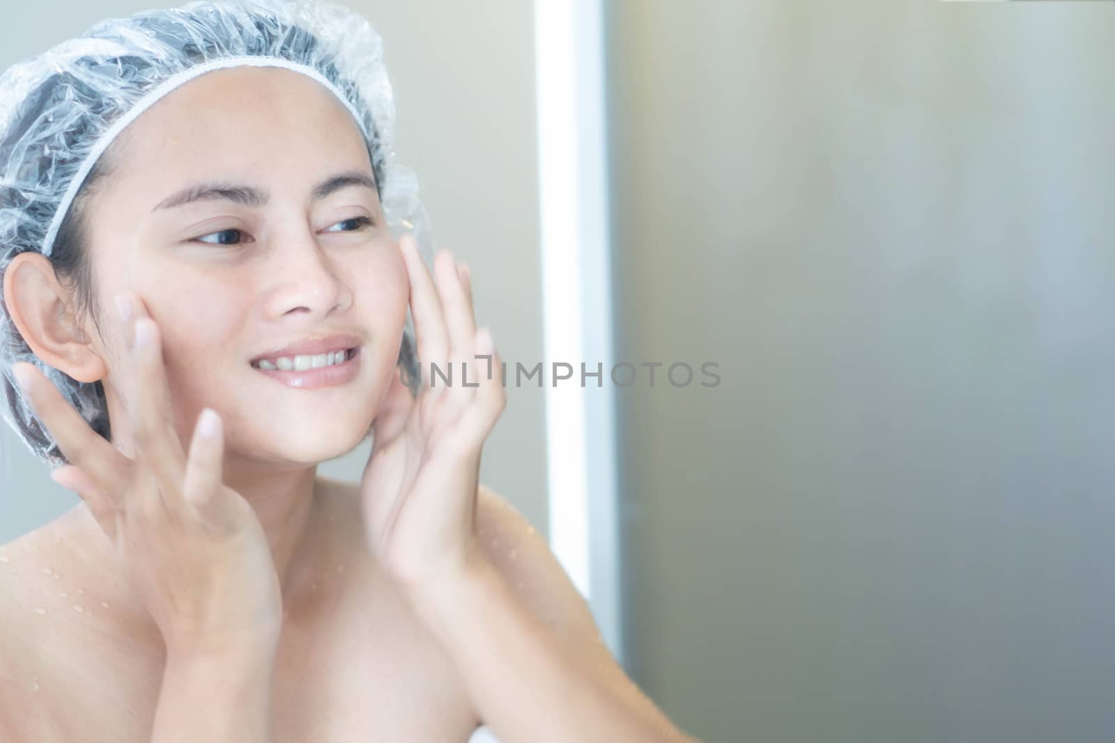 Close up woman looking her face in the mirror with smiling after bath, health care and beauty