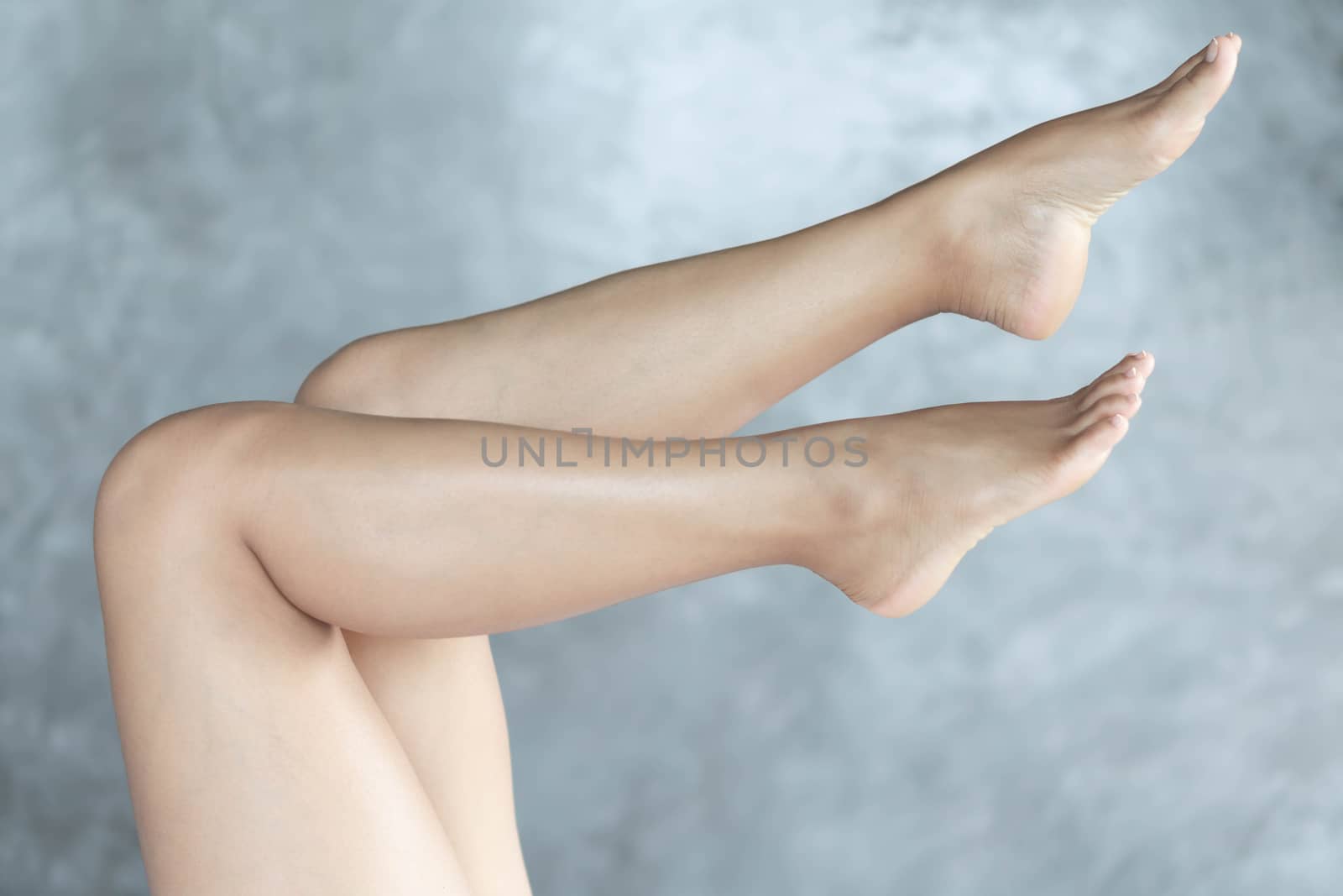Closeup woman legs relaxing with grey background, beauty and skin care concept, selective focus