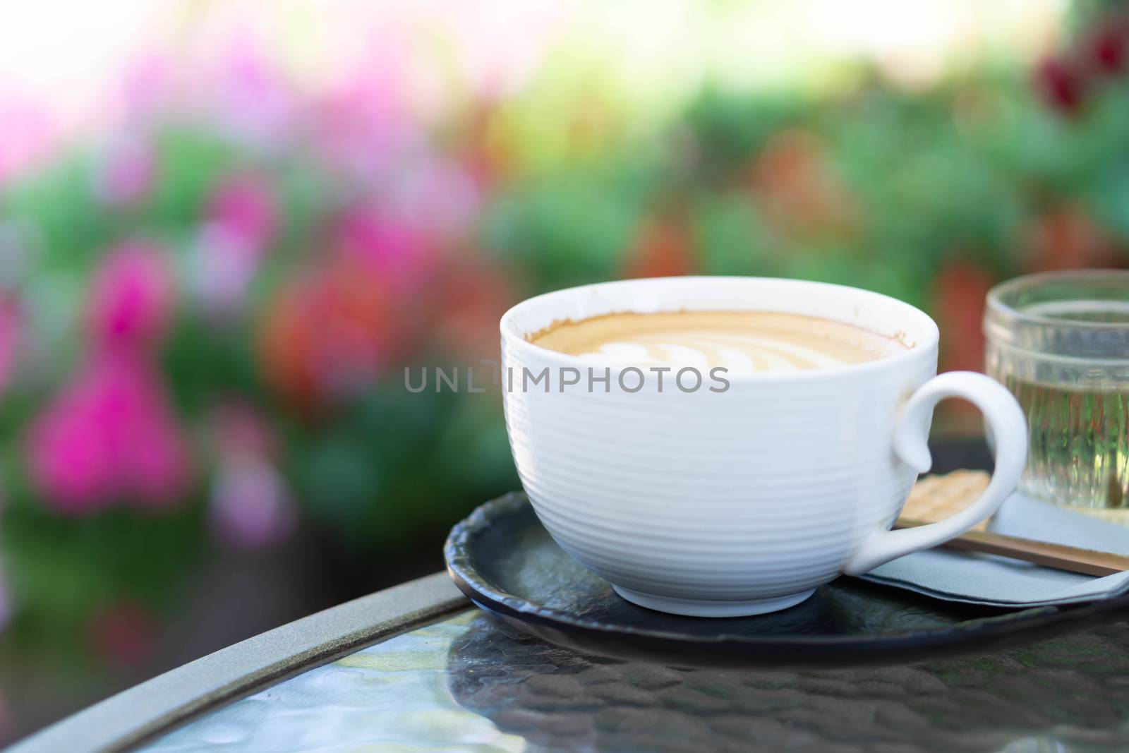 Closeup glass of latte art coffee tulip shape on glass table with flower background