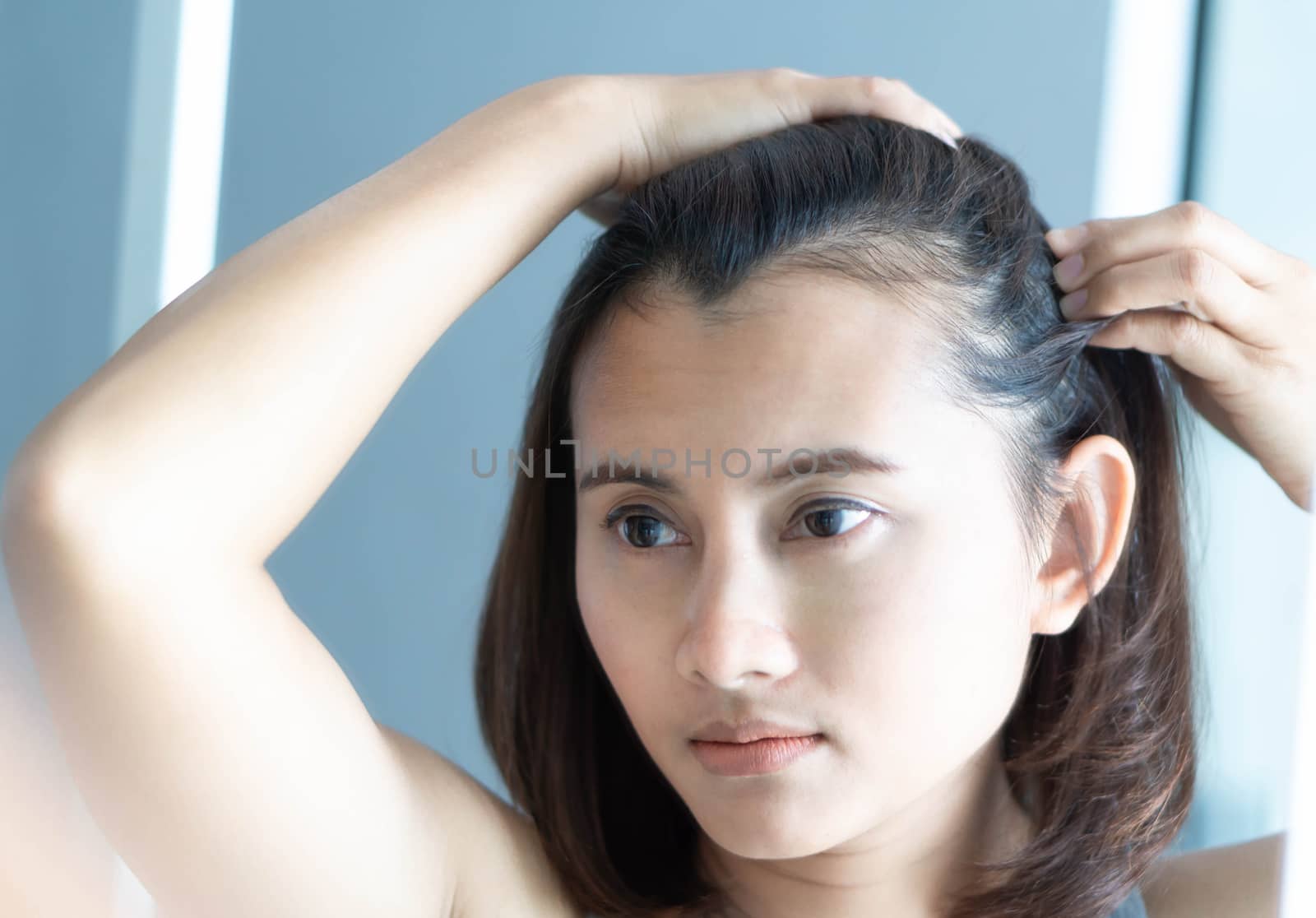 Woman looking reflection in the mirror serious hair loss problem for health care shampoo and beauty product concept