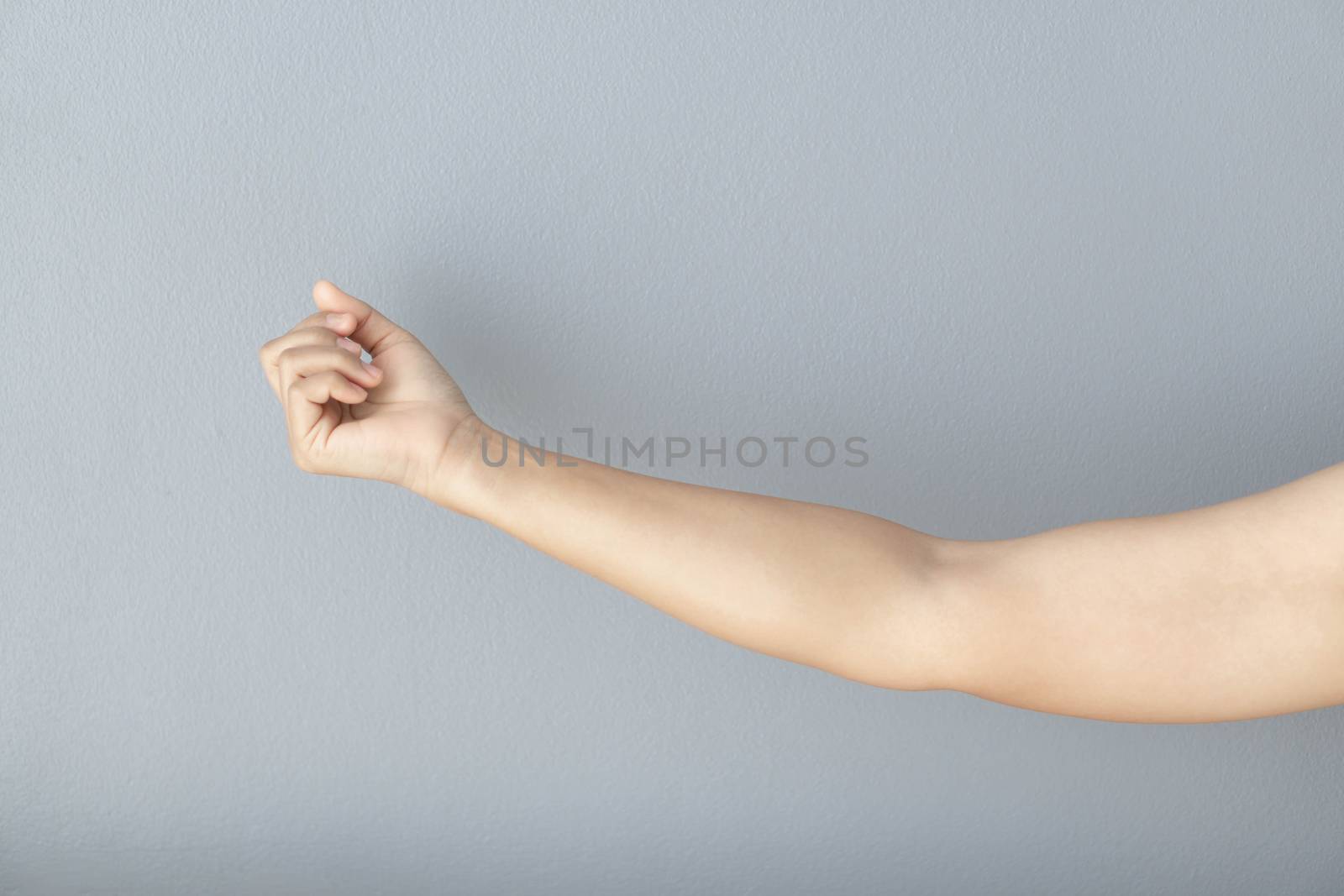woman hand with clenched fist on grey background, health care and medical concept
