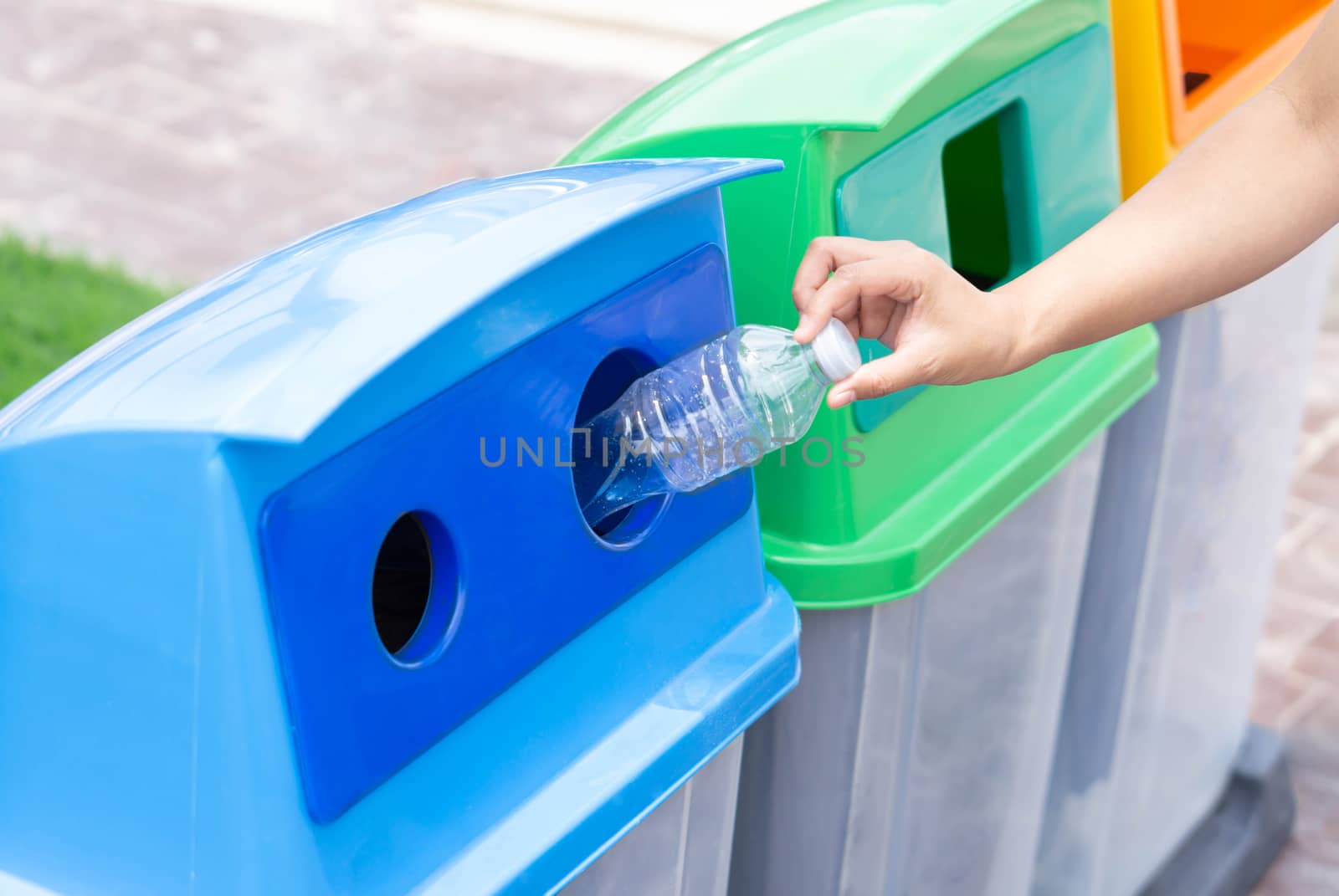 Close up hand holding garbage plastic bottle into recycle trash bin, selective focus