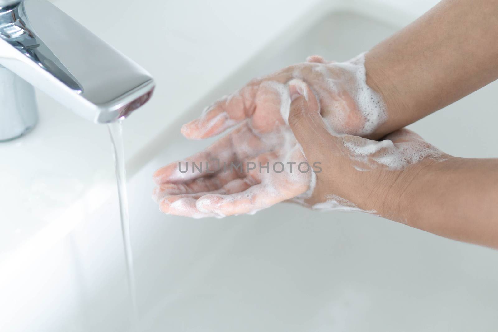 Closeup woman's hand washing with soap in bathroom, selective focus