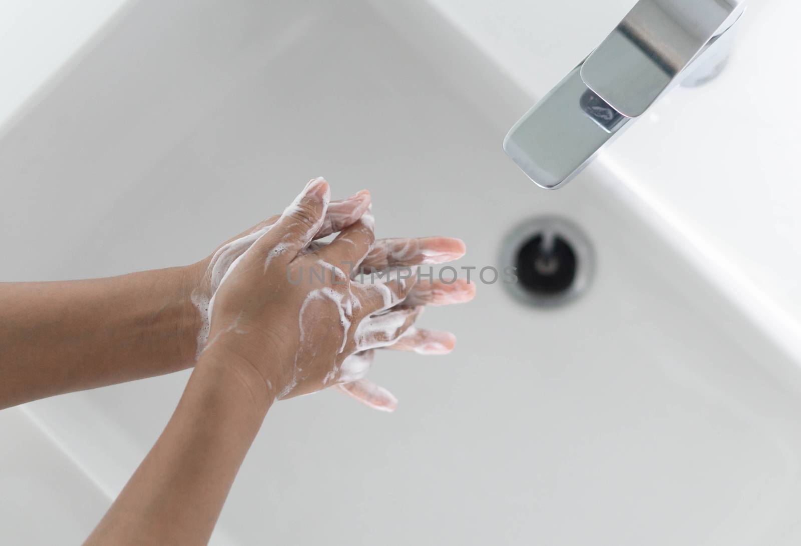 Closeup woman's hand washing with soap in bathroom, selective focus
