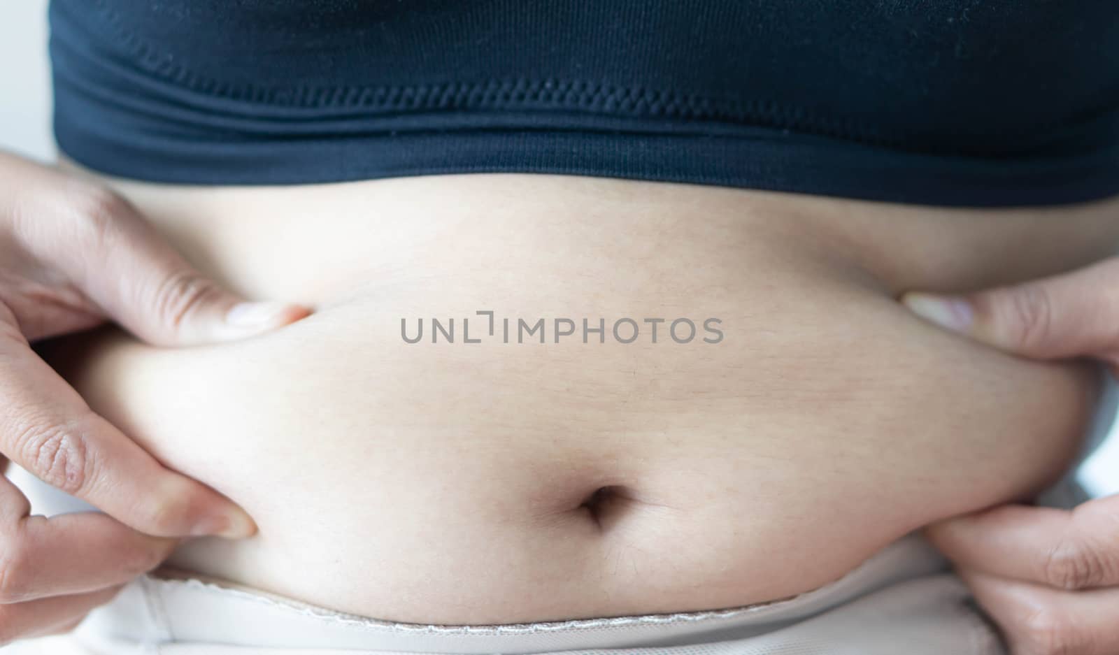 Closeup hand holding abdominal surface woman fat, healthy care and beauty concept