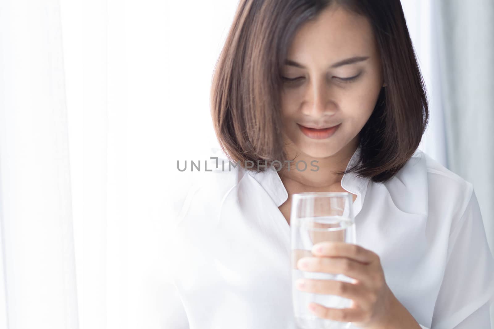 Close up woman drinking pure water from glass with light in the  by pt.pongsak@gmail.com