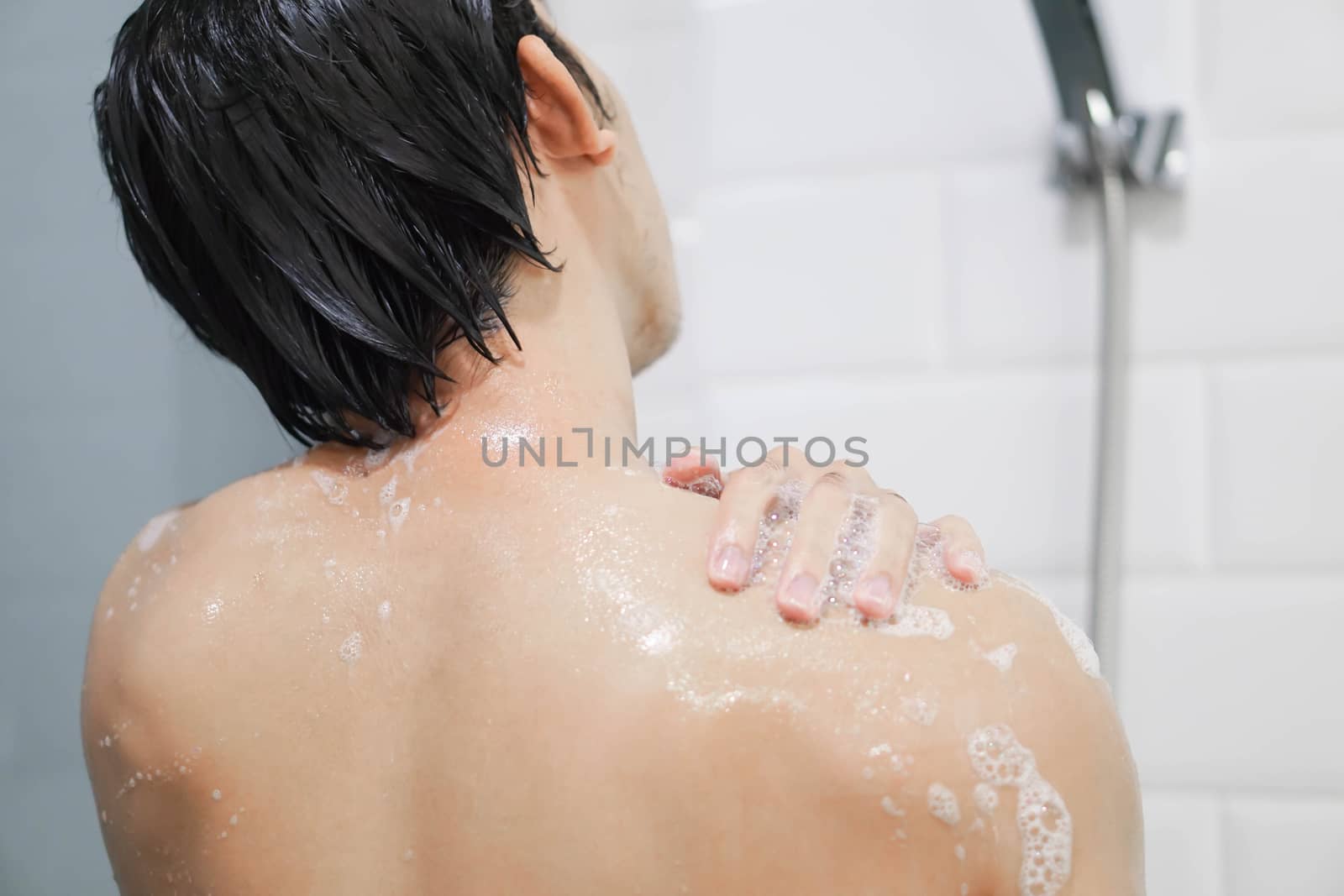 Closeup handsome asian man taking a shower in the bathroom, selective focus