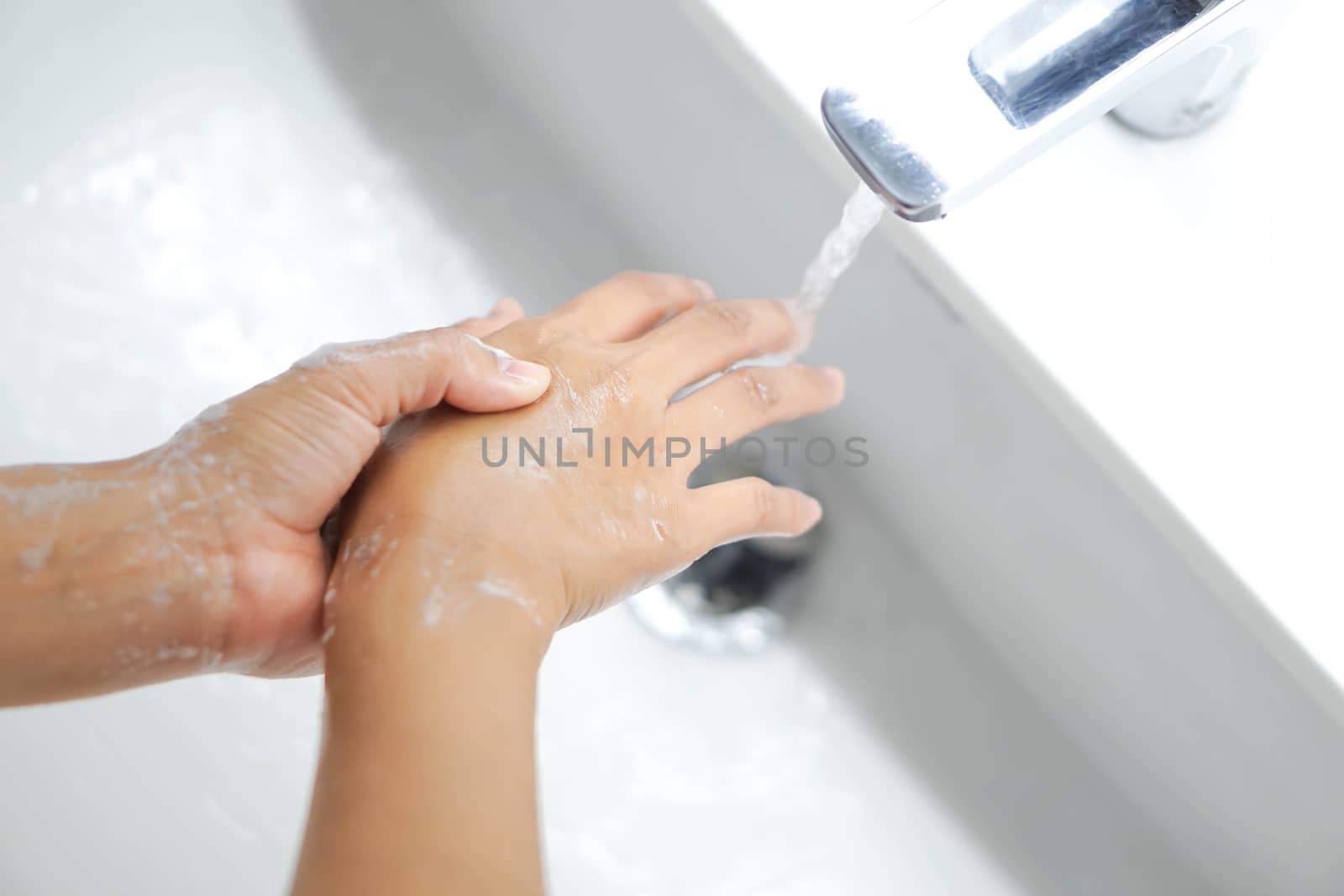 Closeup woman's hand washing with soap in bathroom, selective focus