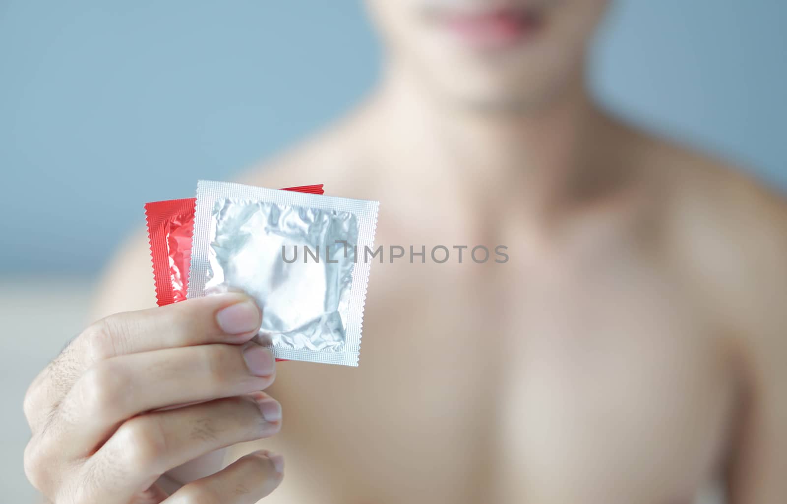 Close up man hand holding condom ready for use  lying on white b by pt.pongsak@gmail.com