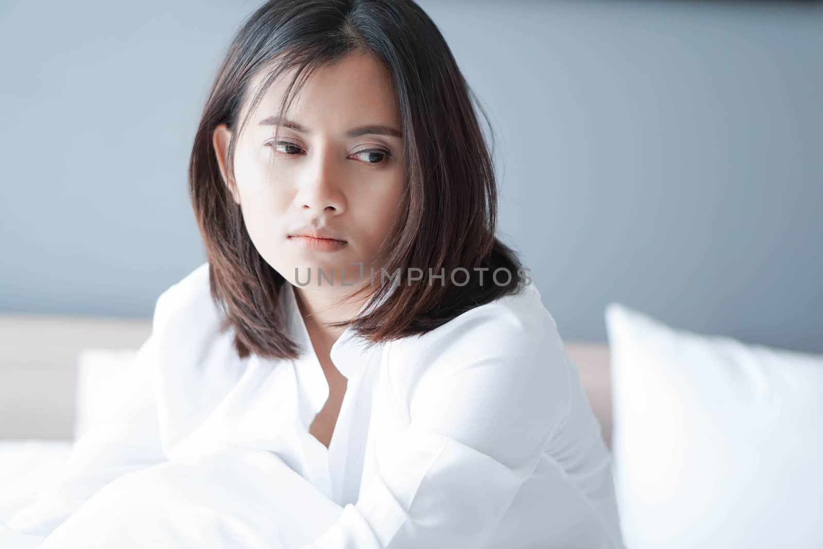 Closeup woman sitting on bed in the bedroom with thinking or depressed feeling, selective focus