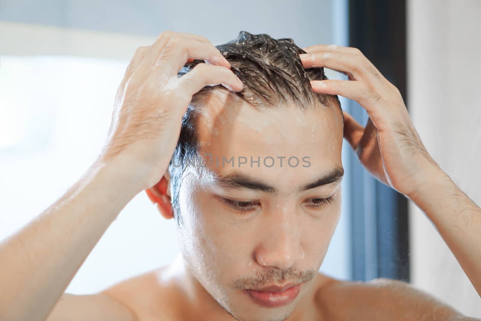 Closeup young man washing hair with with shampoo in the bathroom, vintage tone, selective focus