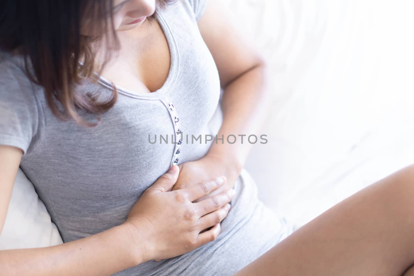 Close up woman stomachache lying on white bed, health care concept, selective focus